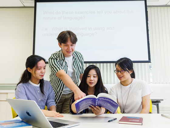 Students reading a book and discussing in a classroom