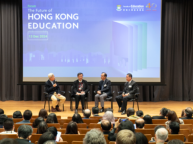 Four speakers engaged in a group discussion on stage 